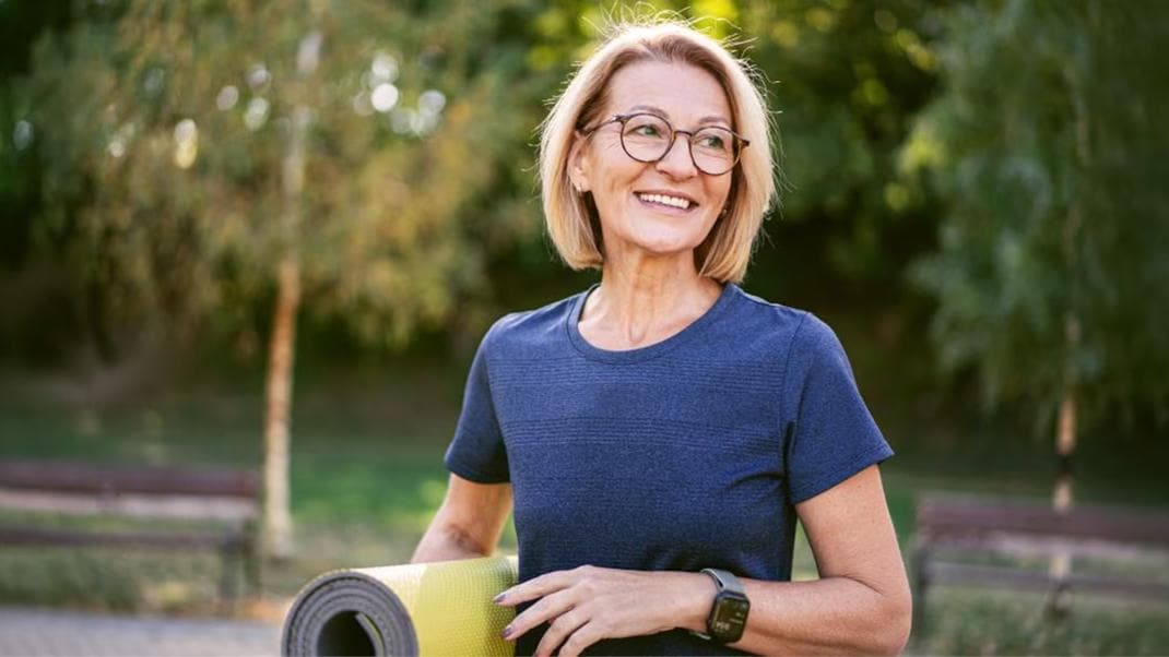 Persona impegnata in attività fisica all'aria aperta con tappetino da allenamento.