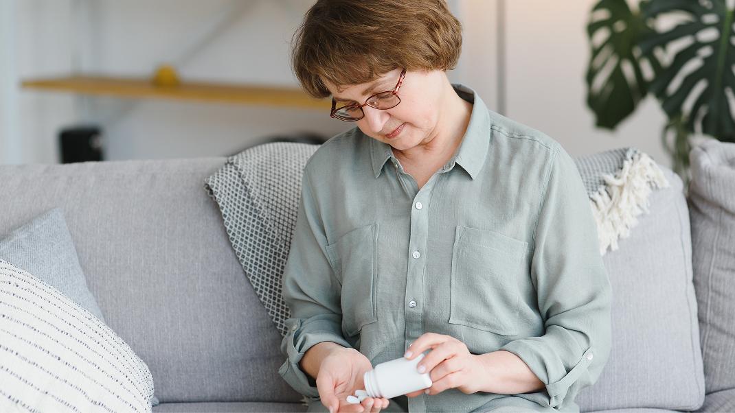 Persona osserva una confezione di farmaci prima dell'assunzione della terapia.