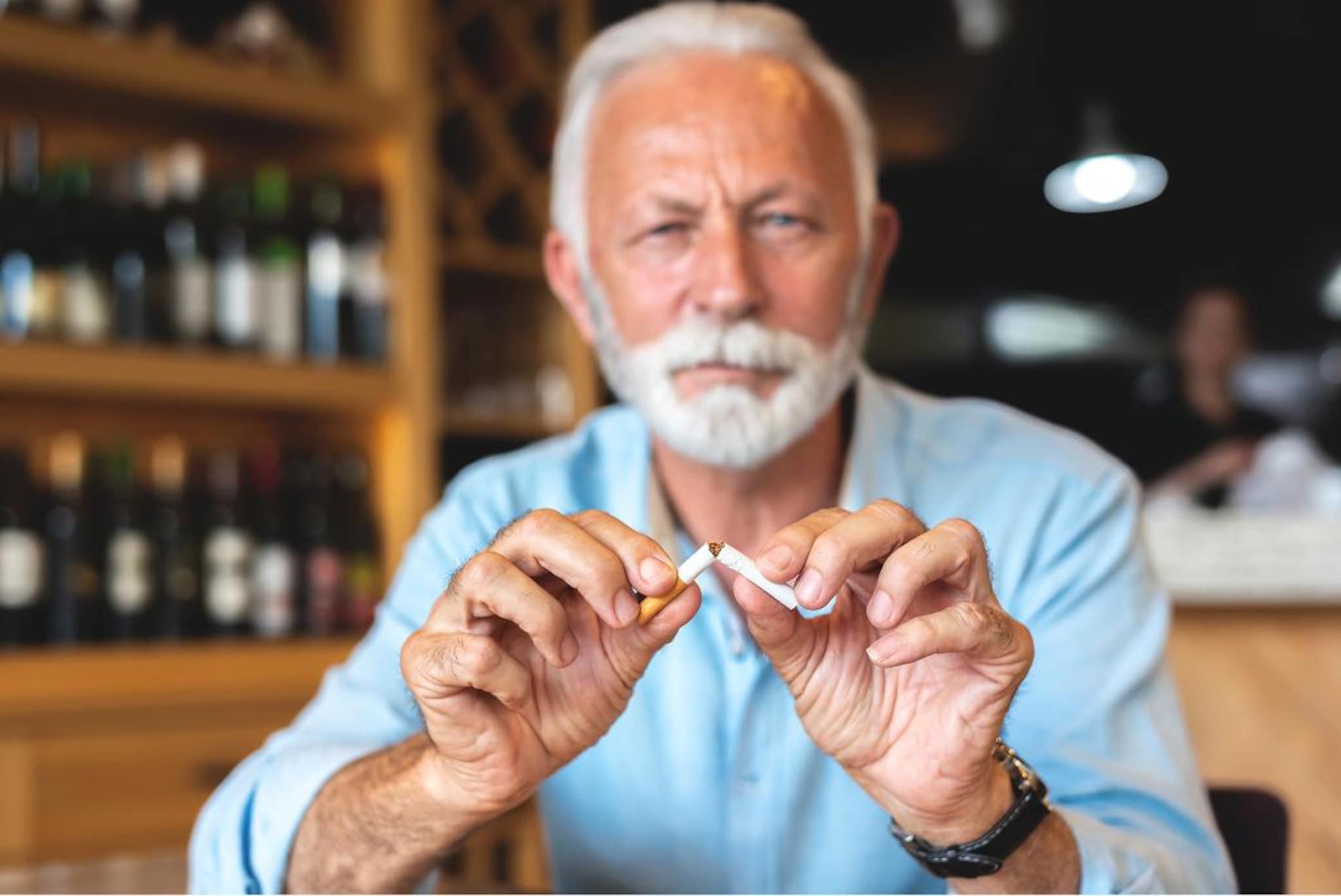Persona spezza una sigaretta con le mani come simbolo della cessazione del fumo e della prevenzione cardiovascolare.