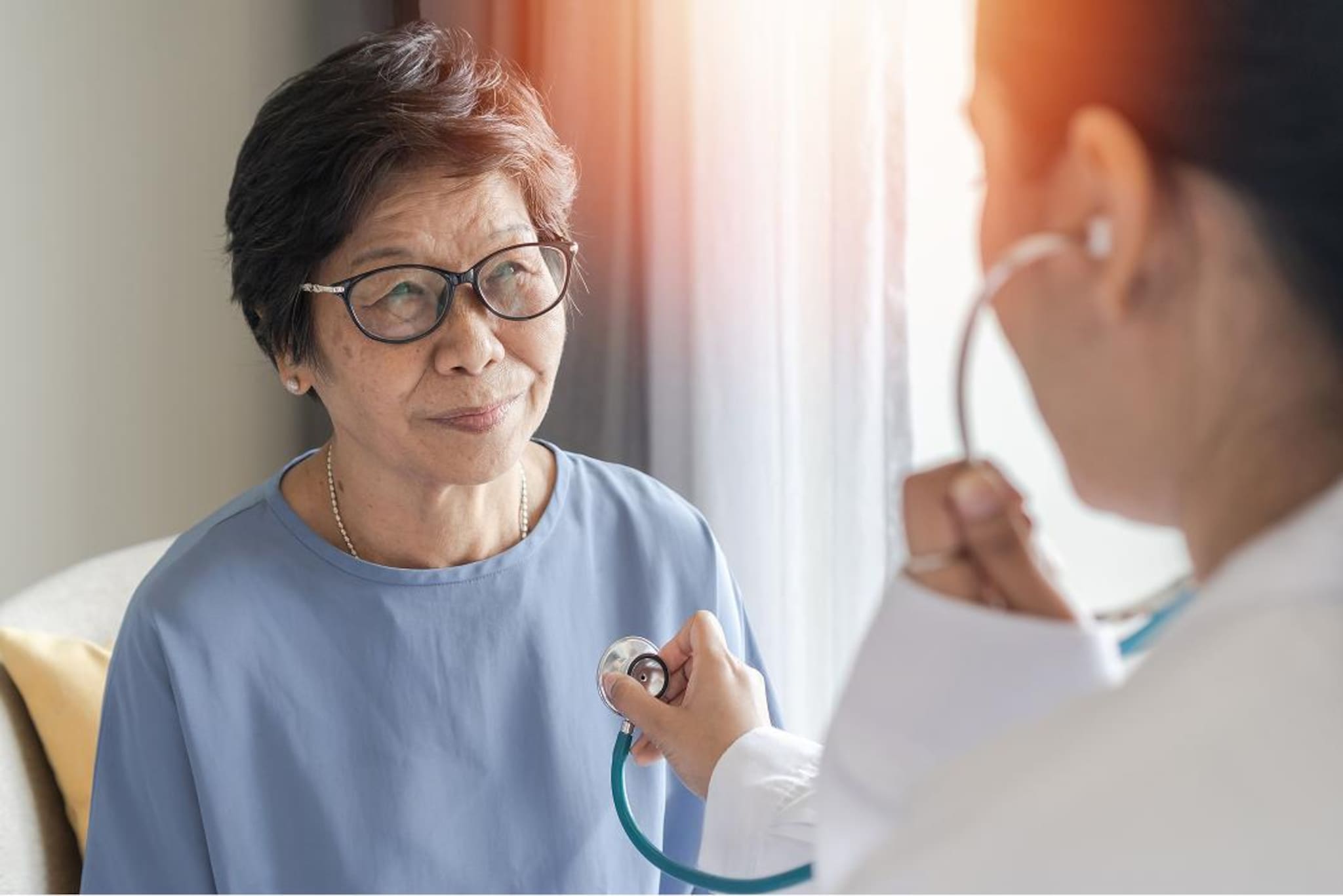 Persona seduta durante una visita medica, mentre un professionista sanitario si appresta ad ascoltare il torace con uno stetoscopio.