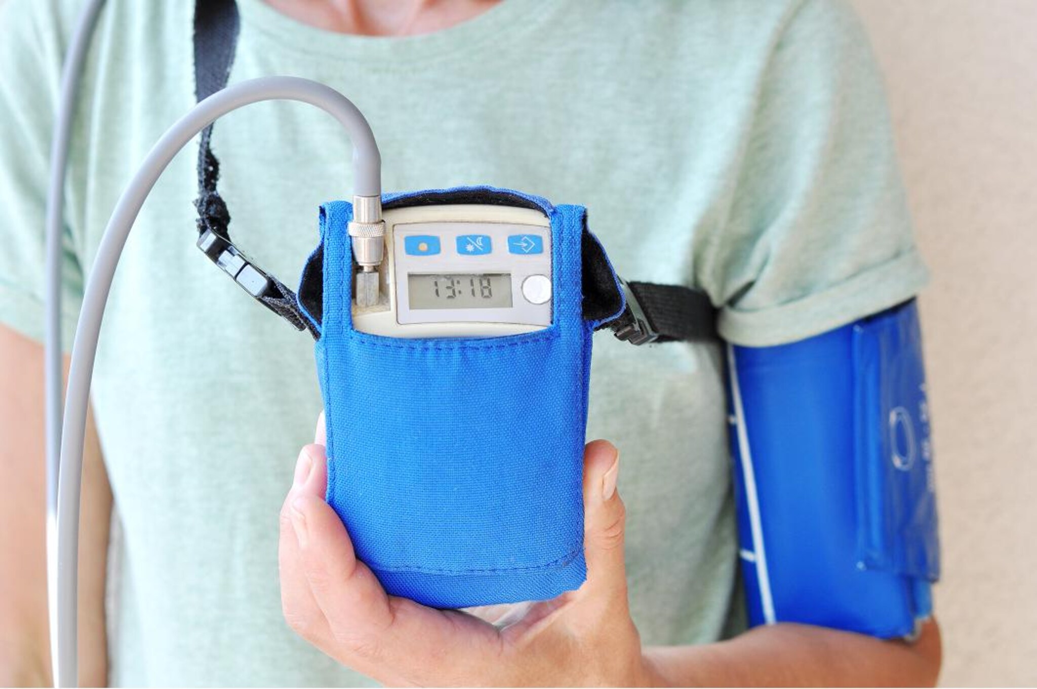 Primo piano di un misuratore portatile collegato a un bracciale per il monitoraggio della pressione arteriosa.