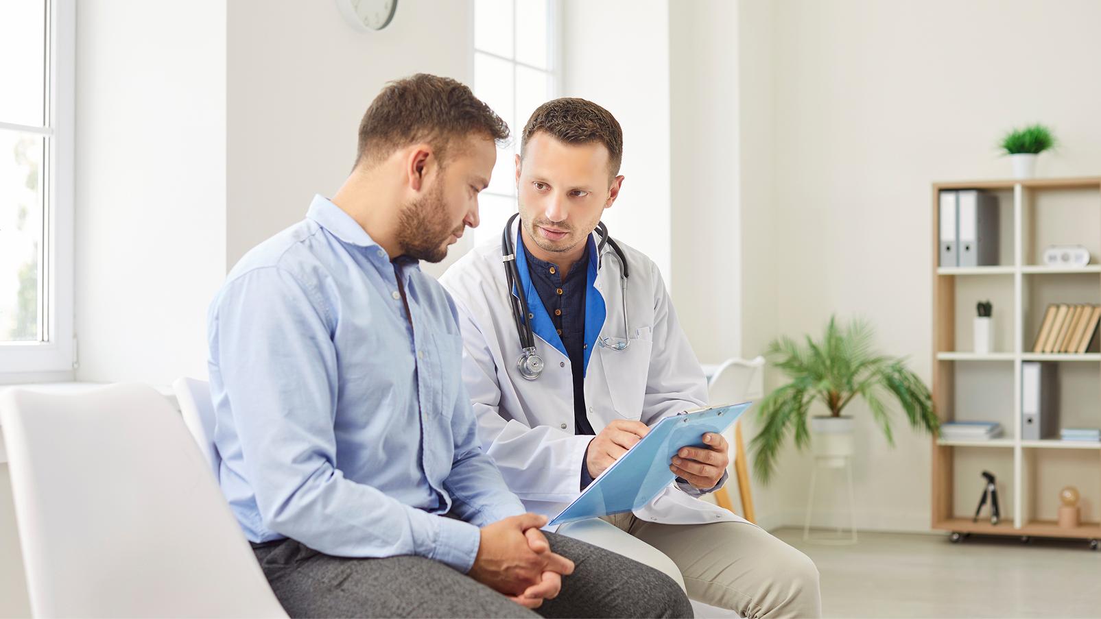 Professionista sanitario che conversa con una persona durante una visita medica.