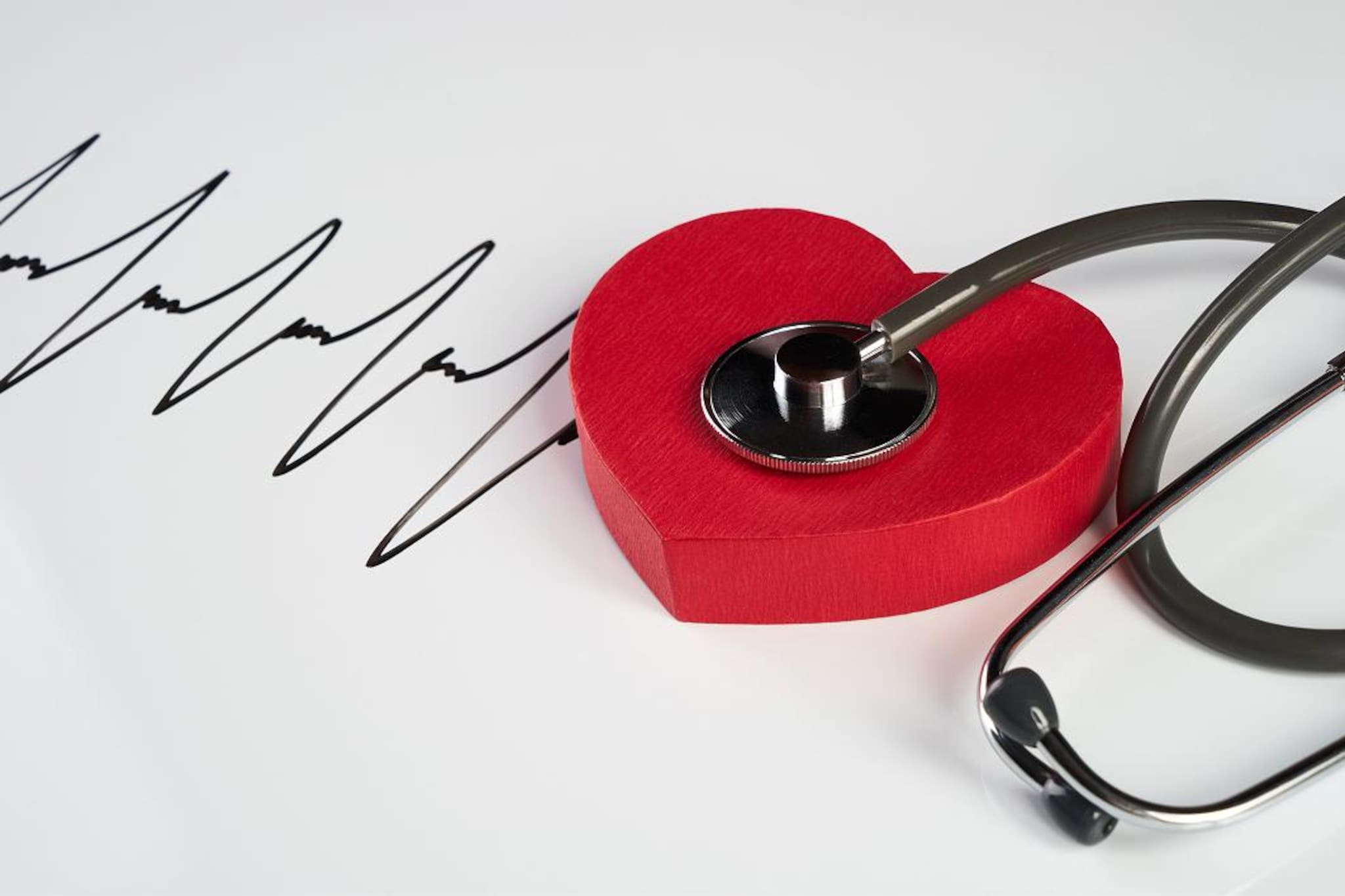 Stetoscopio appoggiato su un cuore rosso stilizzato, accanto a un tracciato grafico che richiama un elettrocardiogramma.