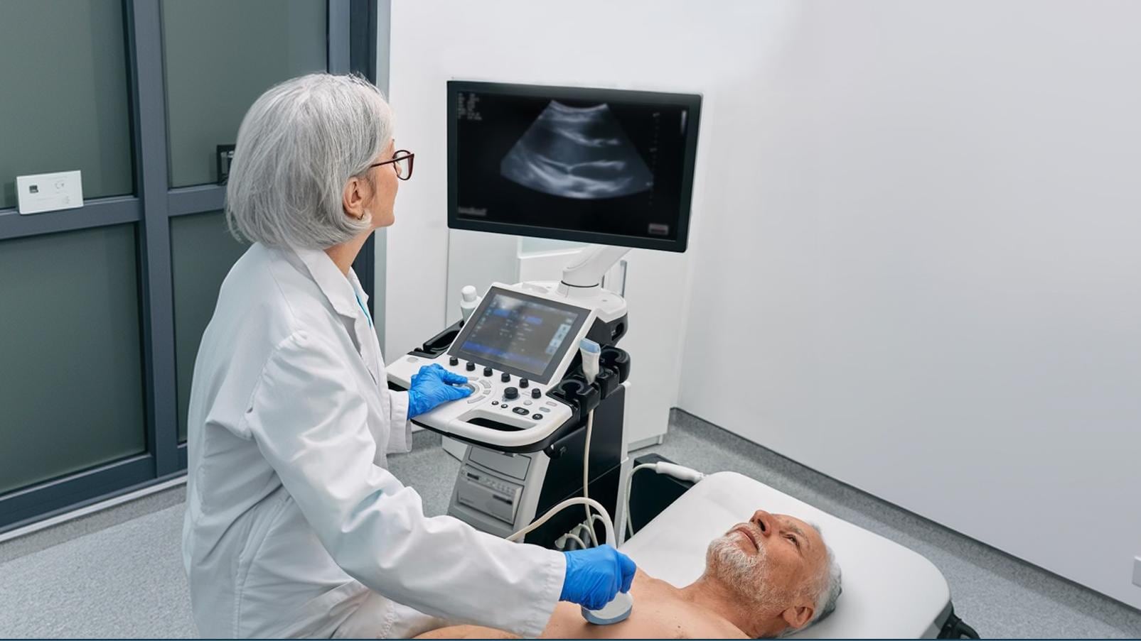 Professionista sanitario esegue un'ecografia del torace su una persona distesa su un lettino, osservando le immagini visualizzate sul monitor dell'ecografo.