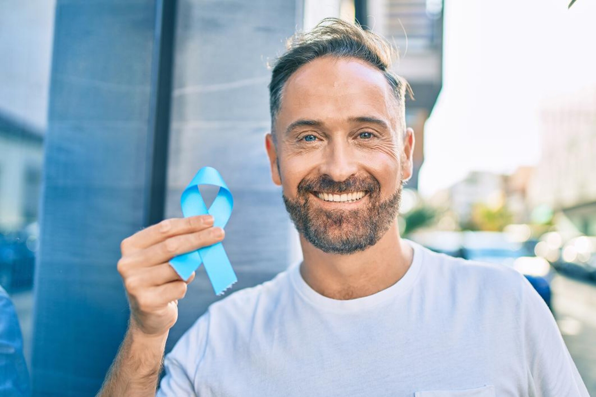 Persona mostra un nastro azzurro simbolo della sensibilizzazione sui tumori della prostata.